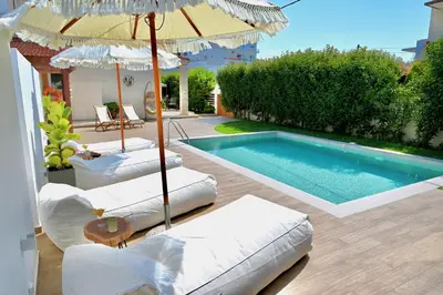 a swimming pool with two lounge chairs and an umbrella at Mediterranean Luxury Villa in Ialyssos