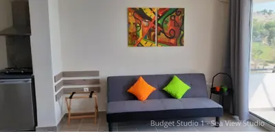 a living room with a blue couch with orange and green pillows at Budget Studios Haraki in Haraki