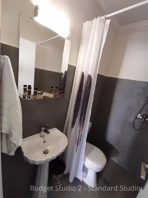 a bathroom with a sink and a toilet and a mirror at Budget Studios Haraki in Haraki