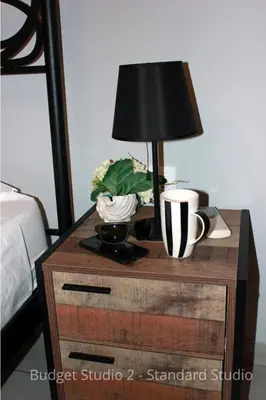 a nightstand with a lamp and a plant on it at Budget Studios Haraki in Haraki