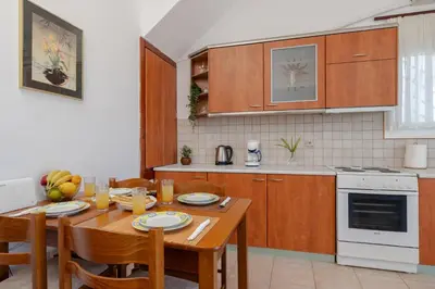 a kitchen with a wooden table with chairs and a dining room at ALBATROS SUITE STEGNA BEACH in Archangelos