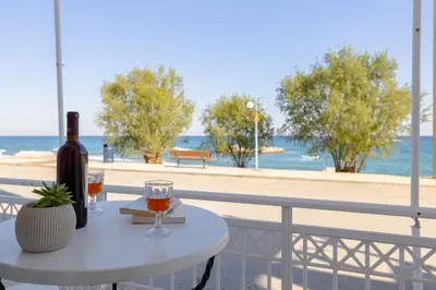 a table with a bottle of wine and glasses on a balcony at ALBATROS SUITE STEGNA BEACH in Archangelos