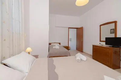 a bedroom with two beds and a tv on a dresser at ALBATROS SUITE STEGNA BEACH in Archangelos