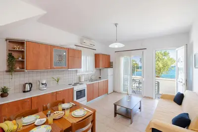 a kitchen and living room with a table and a couch at ALBATROS SUITE STEGNA BEACH in Archangelos