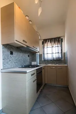 a small kitchen with wooden cabinets and a window at Villa Stamatina in Pastida