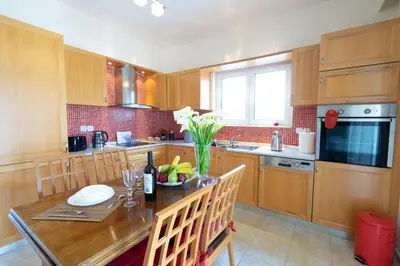 a kitchen with wooden cabinets and a table with a vase of flowers at Alkion Villa in Gennadi