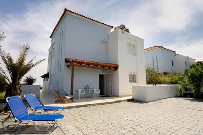 a patio with two blue chairs and a building at Alkion Villa in Gennadi
