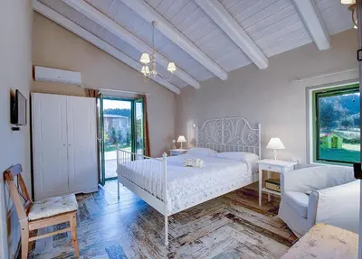 a bedroom with a white bed and a chair at Rhodian Gaea Villa in Theologos