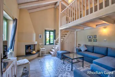 a living room with a blue couch and a staircase at Rhodian Gaea Villa in Theologos