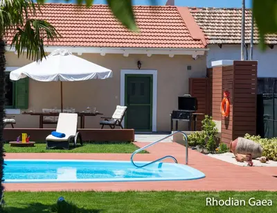 a swimming pool in front of a house at Rhodian Gaea Villa in Theologos