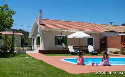 two little girls sitting next to a swimming pool at Rhodian Gaea Villa in Theologos
