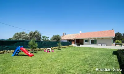 a yard with a playground and a house at Rhodian Gaea Villa in Theologos