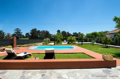 a swimming pool with lounge chairs in a yard at Rhodian Gaea Villa in Theologos