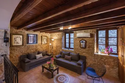 a living room with couches and a stone wall at Rosalia Apartments in Halki
