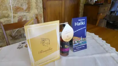 a table with a bag and a bottle of wine and a box at Rosalia Apartments in Halki