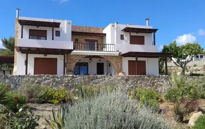 a house on a hill with a stone wall at Blue Harmony Villas in Kiotari