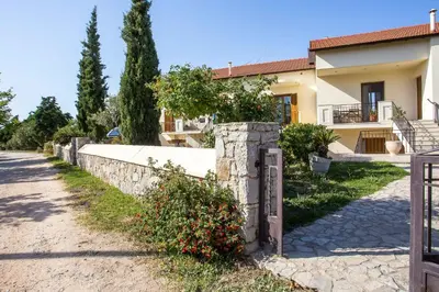 a house with a stone fence in front of a road at Apartment Ivy Kallithea in Rhodes Town