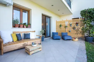 a patio with a wooden couch and blue pillows at Apartment Ivy Kallithea in Rhodes Town