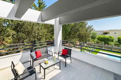 a balcony with red chairs and a table on it at Villa Summer Light in Kiotari