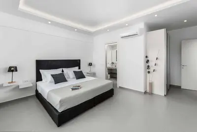 a white bedroom with a large bed and a bathroom at Villa Summer Light in Kiotari