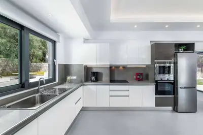a kitchen with white cabinets and a stainless steel refrigerator at Villa Summer Light in Kiotari