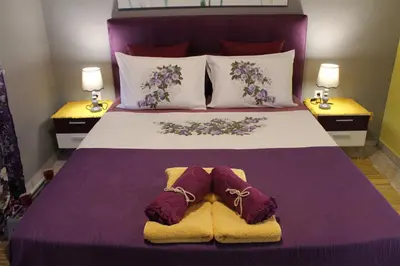 a bedroom with a bed with purple sheets and purple slippers at Lila Studio in Kalathos