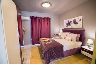 a bedroom with a large bed with purple curtains at Lila Studio in Kalathos