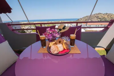 a table with a plate of bread and drinks on a balcony at Lila Studio in Kalathos