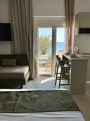 a living room with a couch and a kitchen with a view of the ocean at Stegna Sea & Sun in Archangelos