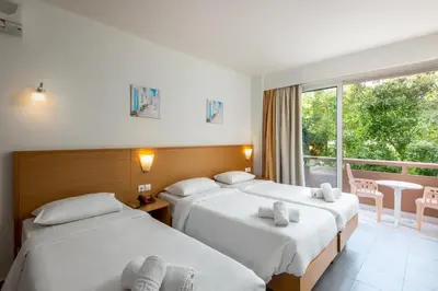 two beds in a hotel room with a window at City Center Hotel in Rhodes Town