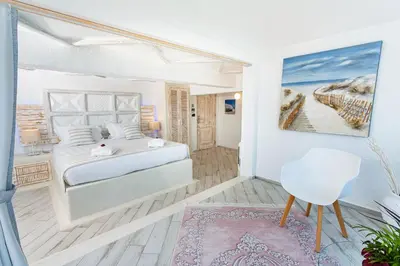 a white bedroom with a bed and a chair at Rhodos Horizon City-Adults Only in Rhodes Town