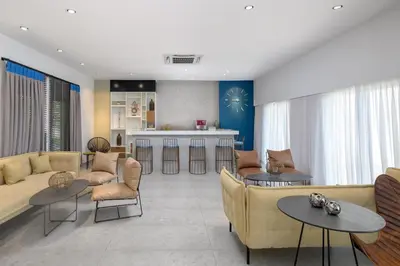 a living room with a couch and tables and a kitchen at Lindos Breeze Beach Hotel in Kiotari