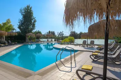 a swimming pool with chairs and an umbrella at Lindos Breeze Beach Hotel in Kiotari