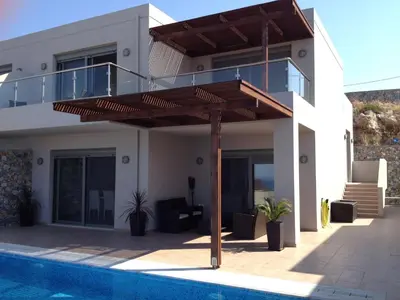 a house with a deck next to a swimming pool at Villa Anna in Pefki Rhodes