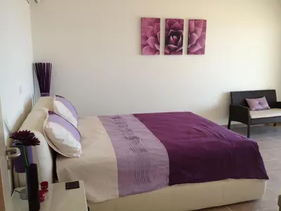 a bedroom with a bed with purple blankets and pillows at Villa Anna in Pefki Rhodes