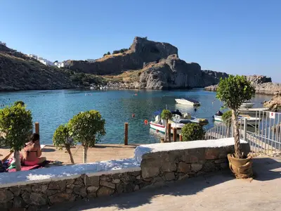 a woman sitting on a wall next to a body of water at Villa Anna in Pefki Rhodes