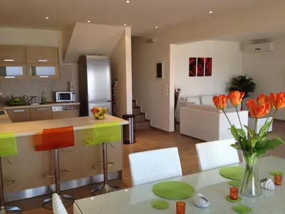 a kitchen and living room with a table with orange flowers at Villa Anna in Pefki Rhodes