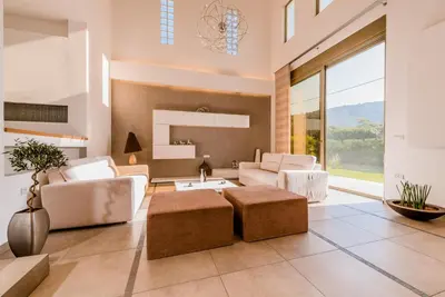 a living room with white furniture and a large window at Filerimos Oasis Luxury Villa in Ialyssos