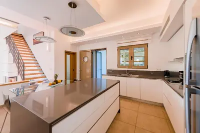 a kitchen with white cabinets and a large island at Filerimos Oasis Luxury Villa in Ialyssos