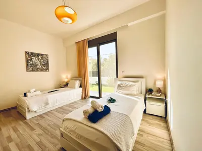 a bedroom with two beds and a large window at Filerimos Oasis Luxury Villa in Ialyssos