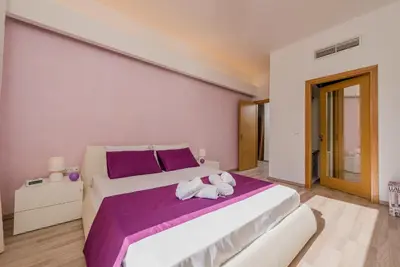 a bedroom with a large white bed with purple sheets at Filerimos Oasis Luxury Villa in Ialyssos