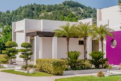 a building with palm trees in front of it at Filerimos Oasis Luxury Villa in Ialyssos