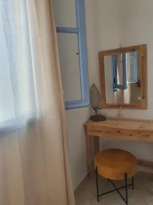 a desk with a mirror and a chair next to a window at Irene Family Apartment in Symi