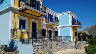 a yellow and white house with balconies and stairs at Irene Family Apartment in Symi