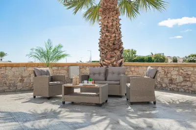 a patio with chairs and a table and a palm tree at Costa Gennadi Villa in Gennadi