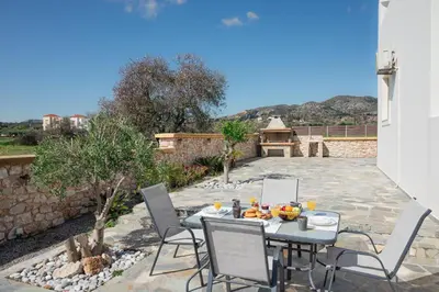 a patio with a table and chairs and a grill at Costa Gennadi Villa in Gennadi