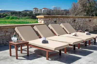 a row of chaise lounge chairs on a patio at Costa Gennadi Villa in Gennadi