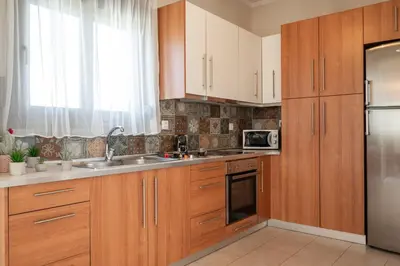 a kitchen with wooden cabinets and a stainless steel refrigerator at Costa Gennadi Villa in Gennadi