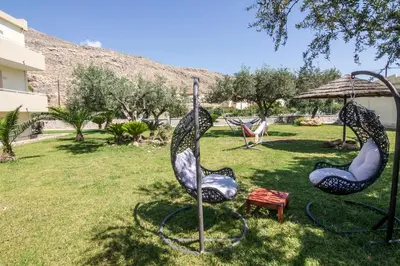 a park with three chairs and an umbrella at Lindos Blue Sky in Líndos