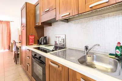 a kitchen with a stainless steel sink and wooden cabinets at Lindos Blue Sky in Líndos